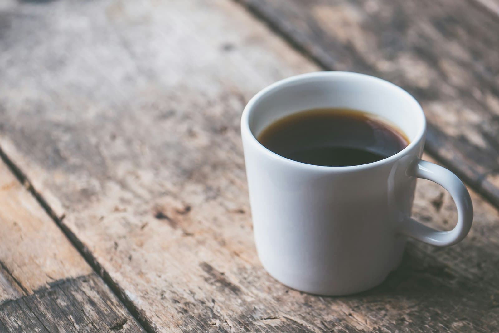 木のテーブルに置かれたブラックコーヒーのマグ